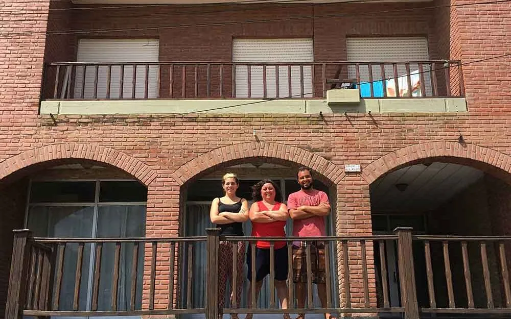 Juan junto a su familia frente a los alojamientos familiares